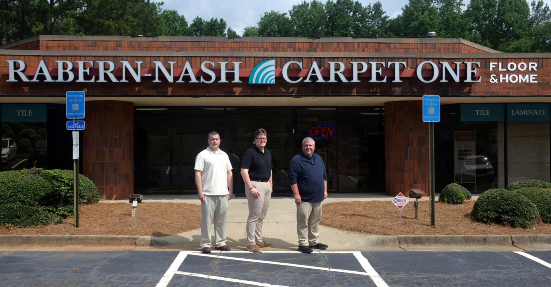 RABERN-NASH CARPET ONE FLOOR & HOME owners of in front of the storefront.